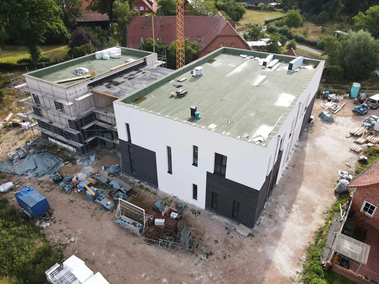 Luftbild der Baustelle: der große Saal rechts, der Anbau links, dahinter das Dorf Anemolter